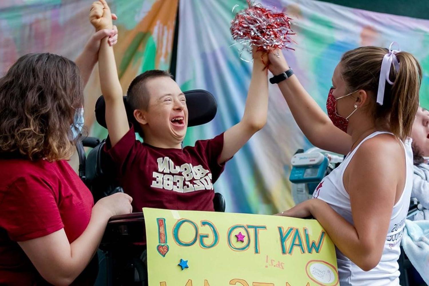 A student cheering while raising both arms in the air