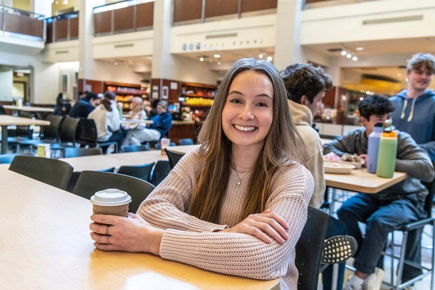 Audrey Smallwood sitting in the dining hall with a cup of coffee